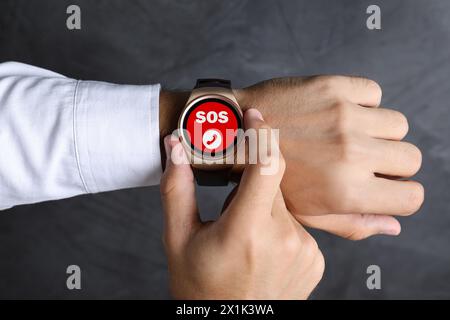 Uomo che utilizza la funzione SOS su sfondo grigio, primo piano Foto Stock