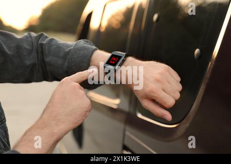 Uomo che utilizza la funzione SOS su uno smartwatch all'aperto, primo piano Foto Stock