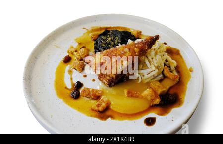 Bicchierino di pancia di maiale croccante, budino nero e salsa di mele su sfondo bianco - John Gollop Foto Stock