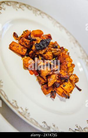 Medley di verdure arrosto gourmet su piatto ornato Foto Stock