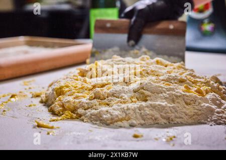 Preparazione artigianale dell'impasto, mani con i guanti e raschietto - primo piano della cucina Foto Stock