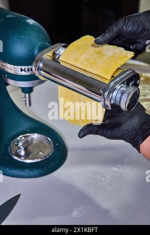 Preparazione di pasta artigianale con mixer da cucina, mani con guanti, vista a livello dell'occhio Foto Stock