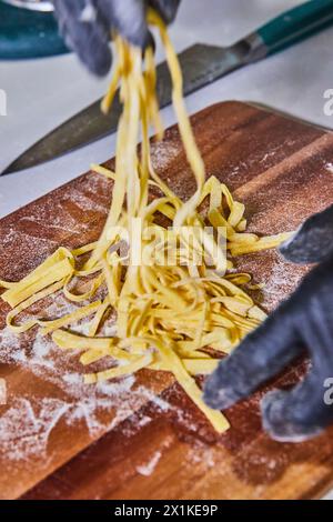 Chef che prepara pasta tagliolini fresca, cucina dinamica in primo piano Foto Stock