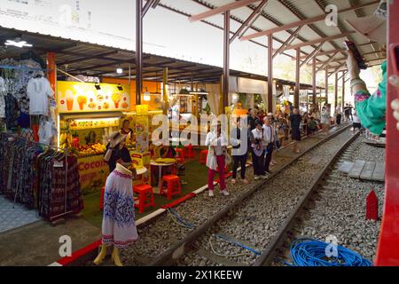Maeklong, Thailandia - i turisti che usano il loro smartphone per catturare il treno che passa attraverso il mercato dei treni vicino alle bancarelle e passa il manichino in pista Foto Stock