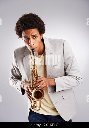 Uomo e musica africana felici, suonando il sassofono con abiti casual e abbigliamento in studio. Musicista sicuro, jazz e strumenti alla moda Foto Stock
