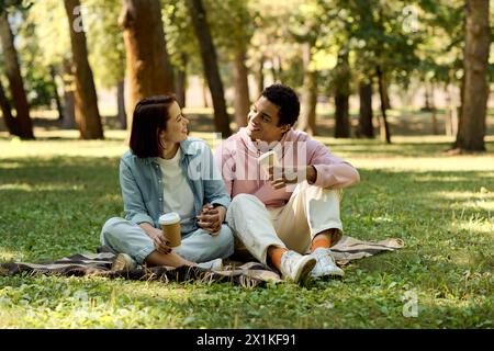 Una coppia variegata in un abbigliamento vivace che si gode un pomeriggio piacevole su una coperta in un parco. Foto Stock
