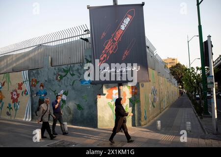 Teheran, Iran. 14 aprile 2024. La gente passa davanti a un poster raffigurante missili iraniani nel centro di Teheran, Iran, domenica 14 aprile 2024. Domenica Israele ha salutato le sue difese aeree di fronte a un attacco senza precedenti da parte dell'Iran, affermando che i sistemi hanno ostacolato il 99% degli oltre 300 droni e missili lanciati verso il suo territorio. (Foto di Sobhan Farajvan/Pacific Press/Sipa USA) credito: SIPA USA/Alamy Live News Foto Stock