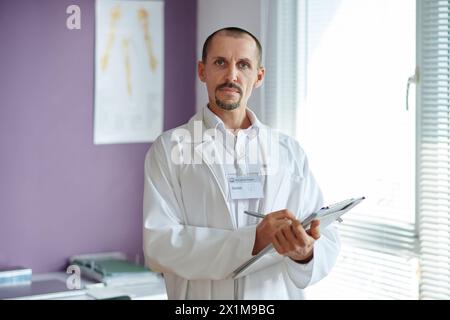Ritratto del medico in camice da laboratorio bianco che prende appunti sul documento Foto Stock