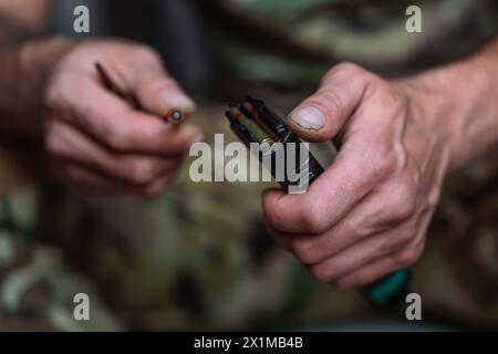 Un primo piano di mani di un militare ucraino carica il caricatore dei fucili d'assalto con cartucce. Caricatore per fucili con cartucce da 5,56 x 45 mm in una mans Foto Stock