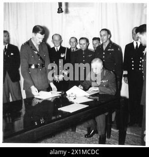 QUARTIER GENERALE DELLE FORZE ALLEATE : ITALIA RESA INCONDIZIONATA - CASERTA, ITALIA AFHQ 29 aprile 1945, TENENTE GENERALE W.D. MORGAN, CAPO DI STATO MAGGIORE A.F.H.Q. firma lo strumento di resa delle forze tedesche in Italia e Austria occidentale per conto del FELDMARESCIALLO SIR HAROLD ALEXANDER, COMANDANTE SUPREMO ALLEATO, TEATRO DELLE OPERAZIONI DEL MEDITERRANEO. Lo strumento di resa è stato firmato poco prima da due plenipotenziari tedeschi. La resa sarà effettiva alle dodici di mezzogiorno G.M.T., MERCOLEDÌ 2 MAGGIO 1945. Guardando, da sinistra a destra, sono:- 1. Tenente colonnello J.G. Sweetman, vice sez Foto Stock