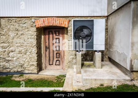 Pompa di calore a sorgente d'aria installata all'esterno di una vecchia casa ristrutturata, concetto di energia rinnovabile verde della pompa di calore Foto Stock