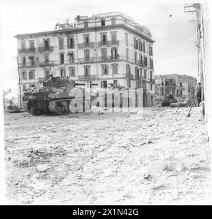 I carri armati dell'Ottava Armata a Ortona si preparano ad attaccare un nido di cecchino, mentre un ufficiale dirige il loro fuoco, durante le operazioni dell'Esercito britannico in Italia. Foto Stock