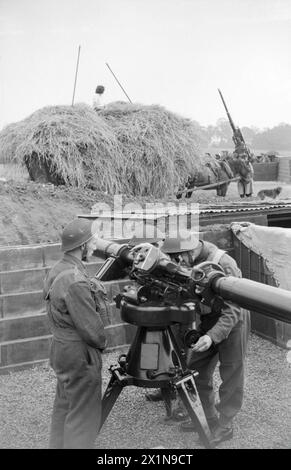 AGRICOLTURA E MILITARI: VITA QUOTIDIANA IN CAMPAGNA, GRAN BRETAGNA, C 1941 - Un fieno, guidato da membri dell'Esercito terrestre femminile, passa da un sito di armi antiaeree, da qualche parte in Inghilterra. Il carro da fieno trainato da cavalli è accatastato e il cane da fattoria può essere visto sullo sfondo, 1941 , Foto Stock