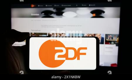 Persona che detiene un cellulare con il logo dell'emittente televisiva Zweites Deutsches Fernsehen (ZDF) davanti alla pagina web. Mettere a fuoco il display del telefono. Foto Stock