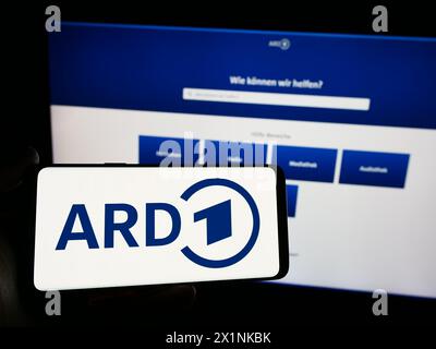 Persona che possiede uno smartphone con il logo dell’ente tedesco di radiodiffusione pubblica ARD davanti al sito web. Mettere a fuoco il display del telefono. Foto Stock