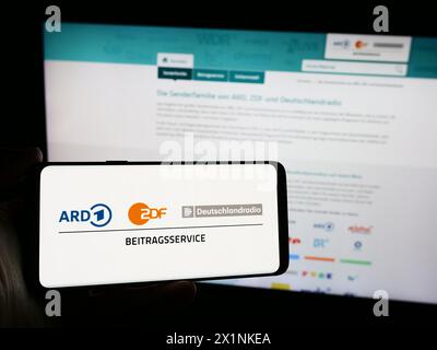 Persona che possiede uno smartphone con il logo di ARD ZDF Deutschlandradio Beitragsservice davanti al sito web. Mettere a fuoco il display del telefono. Foto Stock