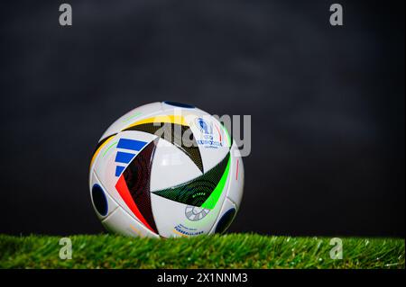LIPSIA, GERMANIA, 17 APRILE 2024: Pallone ufficiale di calcio Adidas Fussballliebe per il torneo di calcio Euro 2024, piazzato su erba verde. Sfondo nero Foto Stock