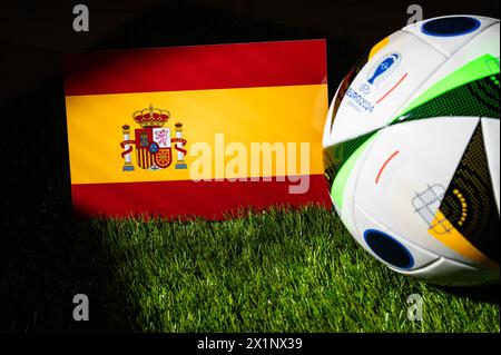 AMBURGO, GERMANIA, 17 APRILE 2024: Bandiera nazionale spagnola e pallone ufficiale di calcio del torneo di calcio Euro 2024 in Germania piazzato su erba verde. Blac Foto Stock