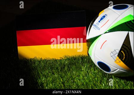 AMBURGO, GERMANIA, 17 APRILE 2024: Bandiera nazionale tedesca e pallone ufficiale di calcio del torneo di calcio Euro 2024 in Germania piazzato su erba verde. BL Foto Stock