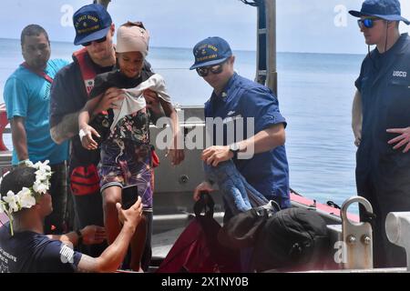 Woleai, Micronesia, Stati Federati di. 12 aprile 2024. L'equipaggio del cutter di pronto intervento classe Sentinel USCGC Oliver Henry carica un bambino di 9 anni ferito per essere trasferito in un ospedale durante una visita per assistere i residenti della remota isola, il 12 aprile 2024 a Woleai, Stato di Yap, Stati Federati di Micronesia. Crediti: CWO Sara Muir/USCG/Alamy Live News Foto Stock