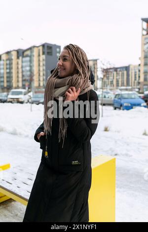 Una bella giovane donna con dreadlocks biondi cammina per la città in inverno Foto Stock