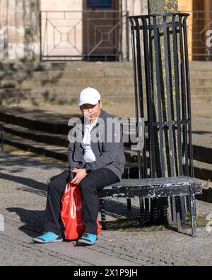 17 aprile 2024. Elgin, Moray, Scozia. Si tratta di un uomo orientale in vacanza che siede godendosi il sole nell'area pedonale di Elgin High Street. Foto Stock