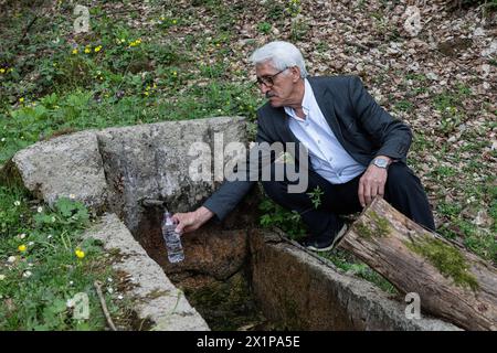 Uomo che riempie l'acqua da una fontana in una bottiglia in natura. Foto Stock