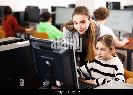 L'insegnante insieme agli studenti conduce una lezione sull'educazione informatica Foto Stock