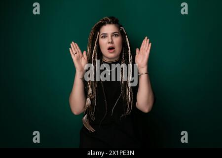 Donna con Dreadlock in piedi davanti allo sfondo verde Foto Stock