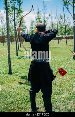 Arciere con arco in abiti tradizionali sparare una freccia Foto Stock