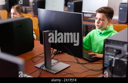 Ha messo a fuoco il ragazzo di Tween che studia con i compagni di classe in laboratorio del calcolatore Foto Stock