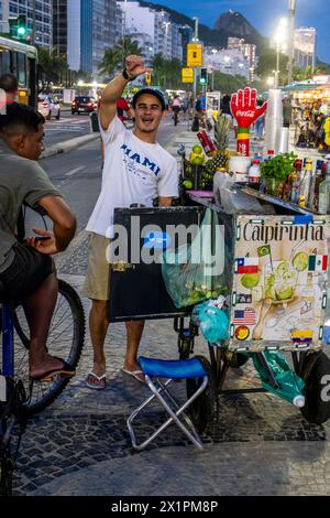 Un uomo vende bevande alcoliche da Un tram/carrello a Copacabana Beach, Rio de Janeiro, Brasile. Foto Stock