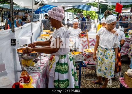 Donne brasiliane in costume tradizionale cucinare e preparare cibo in Un caffè presso il mercato domenicale di Ipanema (Fiera Hippie), Rio de Janeiro, Brasile Foto Stock