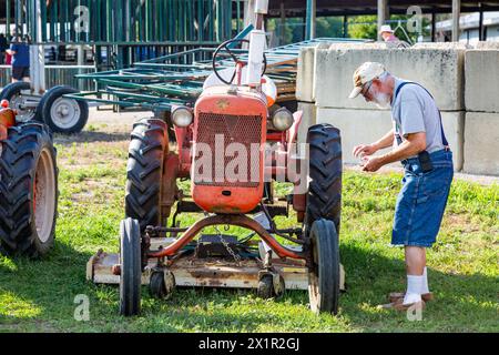 Un agricoltore anziano prepara il suo antico trattore per coltivazione a file Allis Chalmers modello B per essere esposto presso la zona fieristica della contea di Allen a Fort Wayne, Indiana, USA. Foto Stock