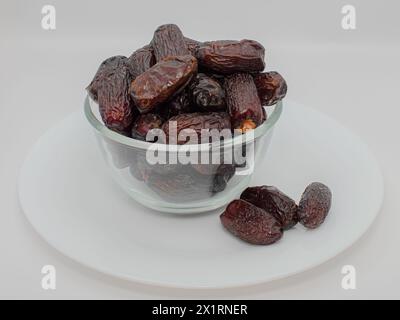 Le datteri safawi nella ciotola di vetro con sfondo bianco le datteri Safawi sono elevate in fibra e potassio, che possono contribuire a migliorare la digestione e la salute generale Foto Stock