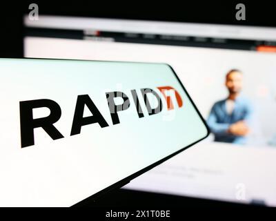 Smartphone con logo della società americana di sicurezza informatica Rapid7 davanti al sito Web aziendale. Mettere a fuoco la parte sinistra del display del telefono. Foto Stock