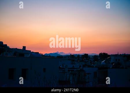 Crogiolati nell'ipnotico bagliore della città mentre il sole tramonta, proiettando una luce calda sul paesaggio urbano. Foto Stock