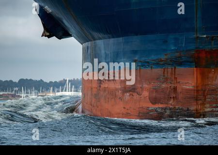 Le grandi navi portacontainer blu si inchinano con ancore arrugginite spinge un'onda di prua gigante attraverso l'oceano. Foto Stock