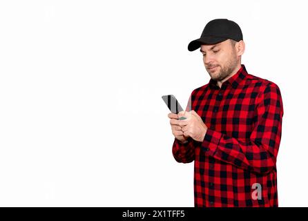Uomo che indossa una camicia casual a quadri rossa e un berretto nero utilizzando il suo smartphone, leggendo e-mail, utilizzando l'app mobile. Foto Stock