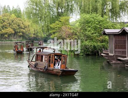 (240418) -- JIAXING (ZHEJIANG), 18 aprile 2024 (Xinhua) -- i turisti visitano la città sull'acqua di Wuzhen su barche a remi nella città di Jiaxing, nella provincia di Zhejiang della Cina orientale, 11 aprile 2024. Situata nella provincia di Zhejiang della Cina orientale, la città sul mare di Jiaxing è rinomata per le destinazioni turistiche del lago Nanhu e Wuzhen. Nel mese di aprile, i due luoghi turistici si animano con il delicato tocco di primavera. Il lago Nanhu, con le sue acque scintillanti e gli alberi di salice che ondeggiano lungo il lago, è uno spettacolo da vedere. Anche la storica città sull'acqua Wuzhen incanta con le sue acque color smeraldo e imbiancate Foto Stock