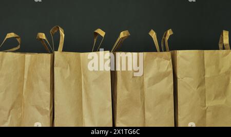 Sacchetti di carta, cartone. Stoccaggio e uso dei sacchetti. Imballaggio della spesa. Sfondo scuro. Copia spazio. Minimalismo Foto Stock