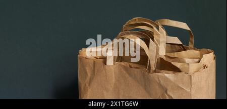 Sacchetti di carta, cartone. Stoccaggio e uso dei sacchetti. Imballaggio della spesa. Sfondo scuro. Copia spazio. Minimalismo Foto Stock