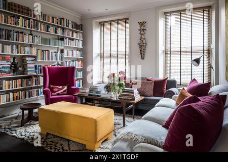 Colori contrastanti e scaffali dei libri con la privacy delle tende veneziane a Chelsea home, Londra, Regno Unito Foto Stock