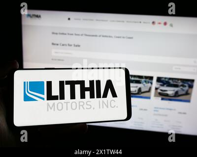 Persona che possiede uno smartphone con il logo della concessionaria automobilistica statunitense Lithia Motors Inc. Davanti al sito Web. Mettere a fuoco il display del telefono. Foto Stock