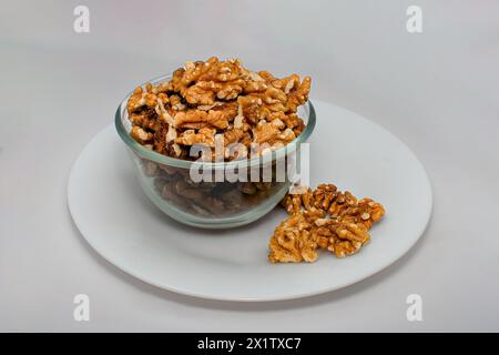 noci nella tazza di vetro, noci tostate con fondo bianco e recipiente di vetro Foto Stock