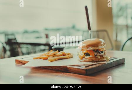 Hamburger tradizionale con patatine fritte servito su un tavolo del ristorante. Hamburger appetitoso con patatine fritte servito su un tavolo di legno Foto Stock