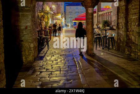 Persona che cammina lungo una strada acciottolata di notte, Traù, Dalmazia, Croazia Foto Stock