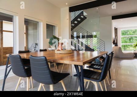 Tavolo da pranzo in legno di noce americano e poltrone in pelle nera con gambe in legno di frassino nella sala da pranzo all'interno di una casa in stile cubo moderno, Quebec, Canada Foto Stock