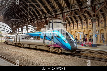 Un treno moderno si trova in una storica piattaforma della stazione ferroviaria sotto una tettoia di ferro del XIX secolo. Alcuni passeggeri si trovano vicino a una colonna. Foto Stock