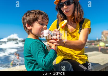 Mamma con suo figlio piccolo che mangia gelato in riva al mare durante le vacanze estive Foto Stock